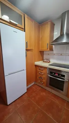 a kitchen with a white refrigerator and wooden cabinets at Vaca House in El Puerto de Santa María