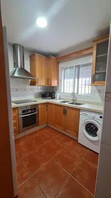 a kitchen with wooden cabinets and a washer and sink at Vaca House in El Puerto de Santa María
