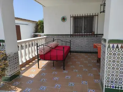 a red bench sitting on a porch with a tile floor at Casa Rural con Piscina Verdugo in El Puerto de Santa María