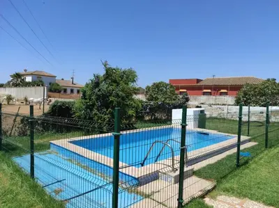a fence around a swimming pool in a yard at Casa Rural con Piscina Verdugo in El Puerto de Santa María