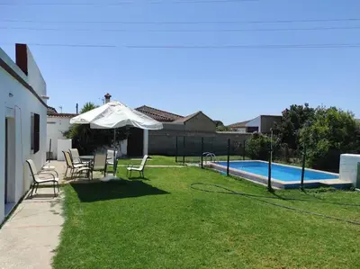 a yard with chairs and an umbrella and a pool at Casa Rural con Piscina Verdugo in El Puerto de Santa María