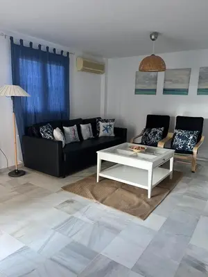 a living room with a black couch and a white coffee table at Fuentebravia House in El Puerto de Santa María