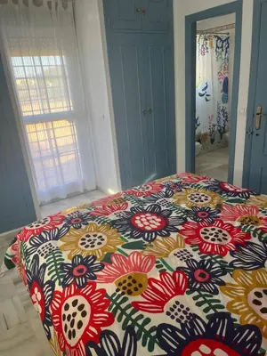a bed in a room with a floral bedspread at Fuentebravia House in El Puerto de Santa María