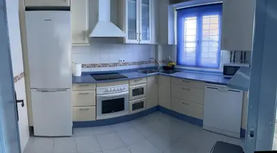 a white kitchen with white appliances and a window at Fuentebravia House in El Puerto de Santa María