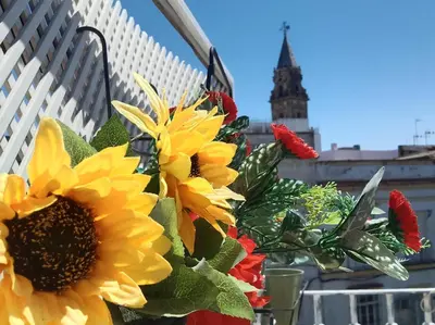 a bouquet of flowers on a balcony with a clock tower at Ático San Agustín - Panoramic View in Jerez de la Frontera