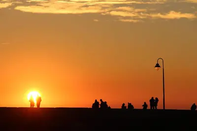 a group of people watching the sunset on the beach at Habana Vieja Cádiz in Cádiz