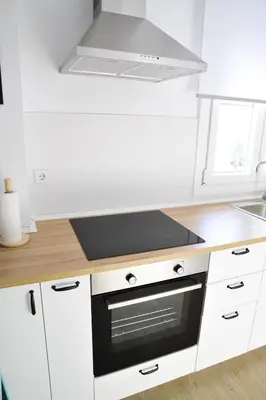 a kitchen with white cabinets and a stove top oven at El Apartamento de Nueva in Cádiz