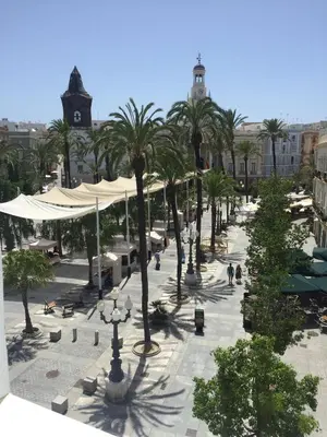 a street with palm trees in a city with buildings at El Apartamento de Nueva in Cádiz