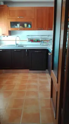 a kitchen with wooden cabinets and a tile floor at Atico con terraza en centro-playa in Sanlúcar de Barrameda