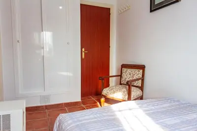 a bedroom with a bed and a chair and a door at Casa de campo, llena de encanto junto al mar in Cádiz