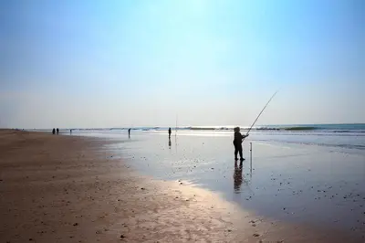 a person standing on the beach holding a fishing rod at Casa de campo, llena de encanto junto al mar in Cádiz