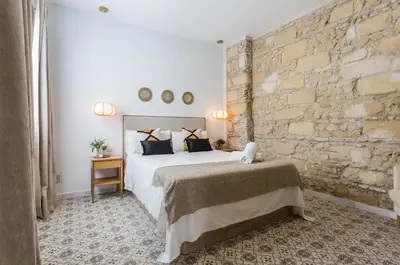 a bedroom with a bed and a brick wall at Apartamento El Mural in Jerez de la Frontera