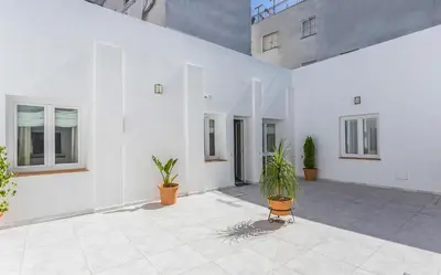 a white building with potted plants in a courtyard at Apartamento El Mural in Jerez de la Frontera