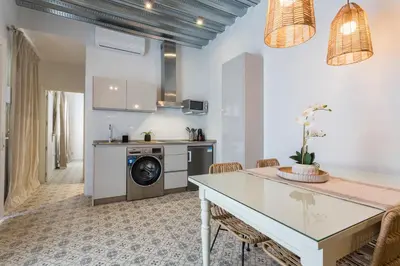 a kitchen and living room with a dining room table and a stove at Apartamento El Mural in Jerez de la Frontera