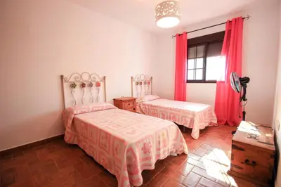 a bedroom with two beds and a window with red curtains at Vivienda Rural El Chirimbolo in Conil de la Frontera