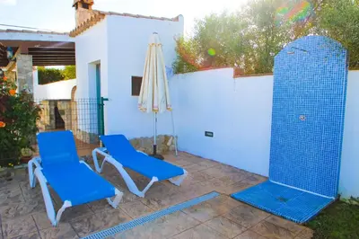 two blue chairs and an umbrella on a patio at Vivienda Rural El Chirimbolo in Conil de la Frontera