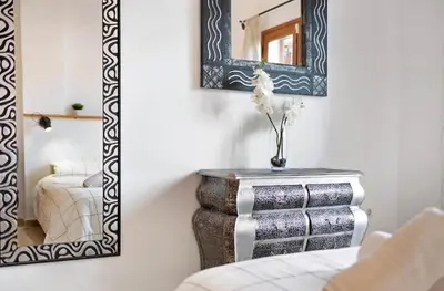 a mirror on a wall next to a table with a chair at Carrajolilla Sancti petri in Chiclana de la Frontera