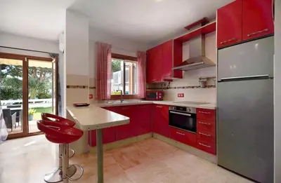 a kitchen with red cabinets and a red chair in it at Carrajolilla Sancti petri in Chiclana de la Frontera