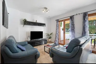 a living room with two blue couches and a television at Carrajolilla Sancti petri in Chiclana de la Frontera