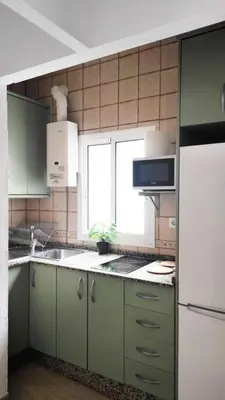 a kitchen with green cabinets and a sink and a window at Acogedor apartamento in Rota