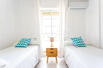 two twin beds in a room with a window at Dúplex 8, en primera línea de playa in Sanlúcar de Barrameda