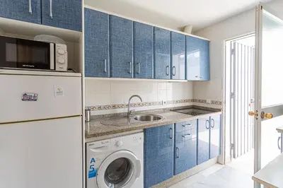 a kitchen with blue cabinets and a washer and dryer at Dúplex 8, en primera línea de playa in Sanlúcar de Barrameda