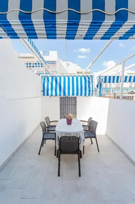 a table and chairs on the upper deck of a ship at Dúplex 8, en primera línea de playa in Sanlúcar de Barrameda