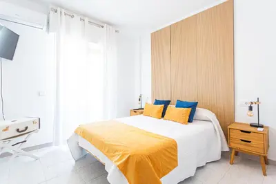a bedroom with a large bed with yellow and blue pillows at Dúplex 8, en primera línea de playa in Sanlúcar de Barrameda