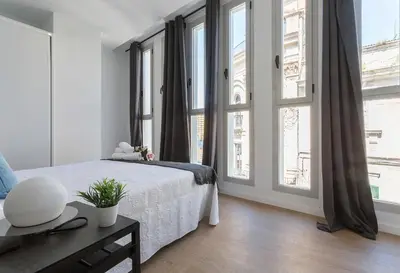 a white bedroom with a bed and large windows at Rianal Céntrico Moderno in Jerez de la Frontera