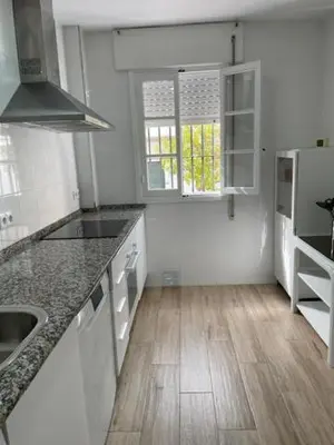 a kitchen with white appliances and a wooden floor at OLEAJE in Sanlúcar de Barrameda