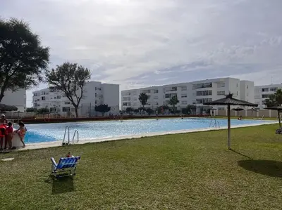 a person sitting in a chair next to a swimming pool at Apto. en la playa del parque natural los Turuños in El Puerto de Santa María
