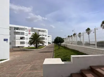 a building with palm trees on the side of a street at Apto. en la playa del parque natural los Turuños in El Puerto de Santa María