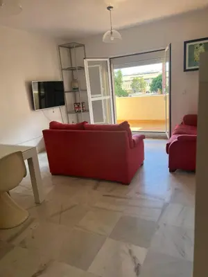 a living room with a red couch and a sliding glass door at Piso de 3 dormitorios con garaje in Jerez de la Frontera