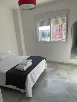a white bedroom with a bed with towels on it at Piso de 3 dormitorios con garaje in Jerez de la Frontera