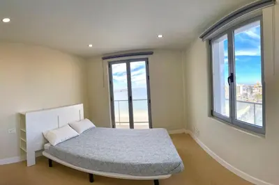 a bedroom with a bed and two windows at Apartamento Fenix - Recién renovado y vistas al mar in Cádiz