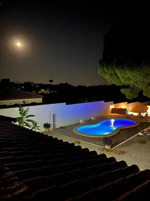 a large blue swimming pool at night next to a lake at CÁDIZ -TIPI en Chiclana de la frontera, España in Chiclana de la Frontera