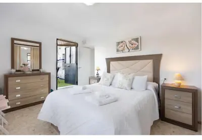 a bedroom with a large white bed and a mirror at La Rosa de Oro in Jerez de la Frontera