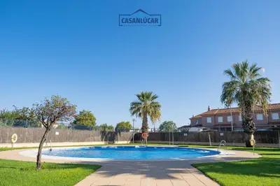 a swimming pool in a park with palm trees at Vivienda Magallanes in Sanlúcar de Barrameda