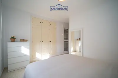a white bedroom with a white bed and a closet at Vivienda Magallanes in Sanlúcar de Barrameda