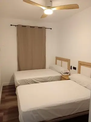 three beds in a room with a ceiling fan at Caímachado in Cádiz