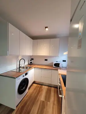 a kitchen with white cabinets and a washing machine at Caímachado in Cádiz
