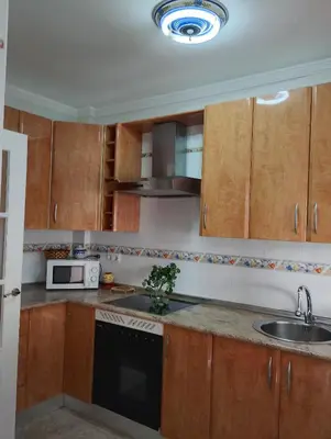 a kitchen with wooden cabinets and a sink and a microwave at LOS MELLIS in Sanlúcar de Barrameda