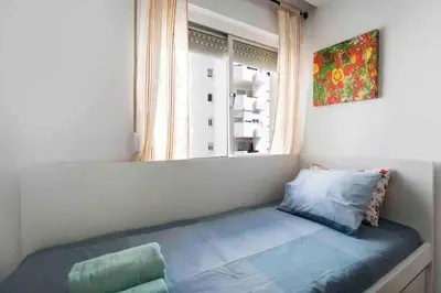 a bed sitting in a room with a window at La casa de la playa in El Puerto de Santa María
