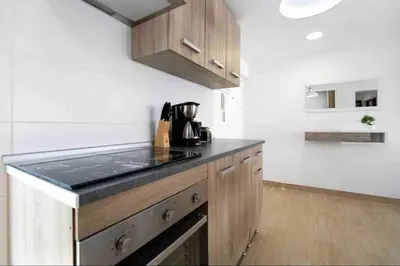 a kitchen with wooden cabinets and a black counter top at La casa de la playa in El Puerto de Santa María