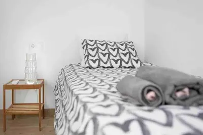 a bed with a black and white blanket and a table at La casa de la playa in El Puerto de Santa María