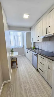 a large kitchen with white cabinets and a wooden floor at Karma loft en la playa by Sanlúcar Housing in Sanlúcar de Barrameda