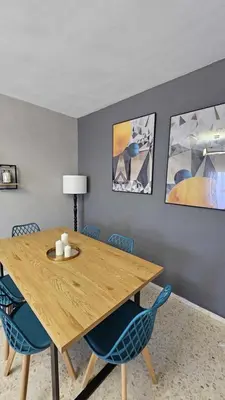 a dining room with a wooden table and blue chairs at Karma loft en la playa by Sanlúcar Housing in Sanlúcar de Barrameda