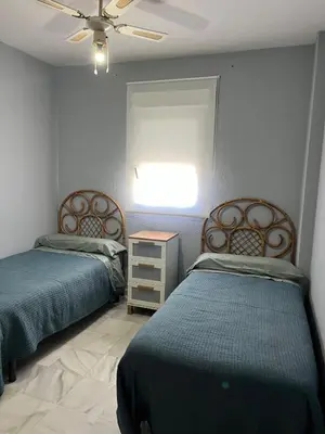 a bedroom with two beds and a dresser and a ceiling at Apartamento Red -primera linea de playa in El Puerto de Santa María