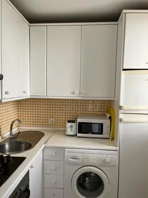 a kitchen with a washing machine and a microwave at Apartamento Red -primera linea de playa in El Puerto de Santa María