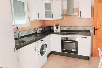a kitchen with white cabinets and a washer and dryer at Chalet Vacacional Chiclana in Chiclana de la Frontera